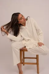 Conjunto de pijama color crema, compuesto por una camisa de manga larga con botones y un pantalón largo con elástico en la cintura ajustable con cordón.