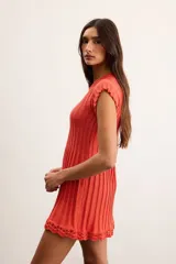 Vestido corto de punto acanalado color naranja, de manga corta y cuello redondo, con detalle de terminación en crochet en el ruedo.
