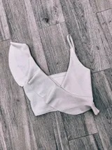 Top de bikini fucsia con un solo tirante y volados en el escote.