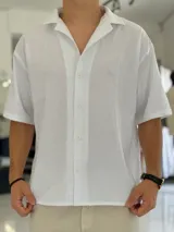 Camisa de lino blanca de manga corta, con cuello abierto tipo cubano, ajuste holgado y cierre frontal con botones.