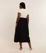 Vestido midi bicolor, con parte superior color crema y falda negra, confeccionado en tejido de punto rib de algodón. Tiene escote redondo y mangas cortas.