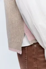 Chaleco de punto color beige con escote en V y ribete blanco.