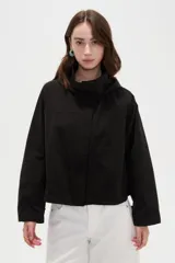 Campera corta de nylon en color negro, con cuello alto, capucha integrada y cierre frontal oculto con solapa.