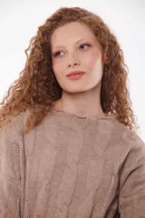 Sweater de punto trenzado color beige, con cuello alto y mangas largas.