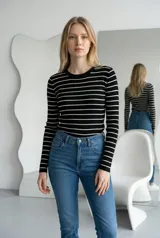 Sweater de hilo de punto con diseño de rayas horizontales negras sobre fondo blanco, cuello redondo y mangas largas.