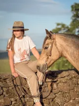 Remera blanca de manga corta con cuello redondo, confeccionada en algodón. Presenta un estampado fotográfico en tono gris oscuro de dos caballos junto al isotipo de la marca en la parte inferior y un aplique marrón en la manga.