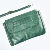 Sobre de mano color verde esmeralda, con solapa de cierre imantado y correa larga desmontable.