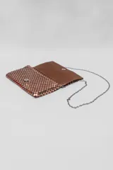 Bandolera pequeña de malla metálica en color cobre, con solapa frontal y cadena larga plateada para llevar al hombro o cruzada.