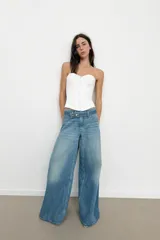 Top tipo corset de escote corazón y hombros descubiertos, con varillas interiores para estructura. Presenta cierre frontal con ganchos metálicos y ajuste en la espalda mediante cordones cruzados.