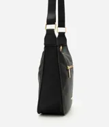 Cartera grande Satinato de color negro, confeccionada en poliéster con detalles en policloruro de vinilo. Posee un diseño moderno con cierre superior, bolsillo frontal con cierre visible y herrajes metálicos dorados, incluyendo una correa ajustable con hebillas y una placa con el logo de la marca.