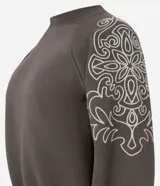 Buzo de moletón con felpa interna, cuello redondo y mangas raglán. Presenta bordados florales en las mangas y terminaciones acanaladas en puños y ruedo.