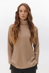 Polera de tejido de punto acanalado en color beige, con cuello alto y diseño de corte recto con aberturas laterales en el ruedo.