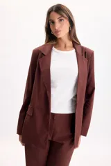 Blazer sastrero de lino color marrón, de líneas clásicas con solapas, bolsillos delanteros con solapa y caída liviana.