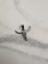 Dije de acero quirúrgico con forma de cráneo de toro, con acabado brillante y argolla superior para cadena.