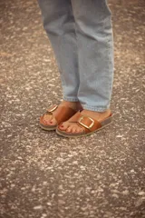 Sandalia marrón de cuero con hebilla dorada, base de corcho y suela beige.