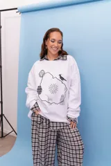 Buzo de cuello redondo en color blanco, con diseño estampado en el centro que incluye el contorno del mapa de Uruguay y símbolos nacionales como el sol, el mate y el hornero.