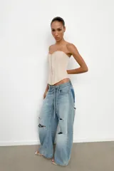 Top tipo corset de escote corazón y hombros descubiertos, con varillas interiores para estructura. Presenta cierre frontal con ganchos metálicos y ajuste en la espalda mediante cordones cruzados.