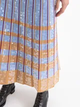 Pollera larga de tejido de punto con diseño de tablas, decorada con lentejuelas bordadas en un patrón de rayas verticales y bloques horizontales en tonos azul y tostado.