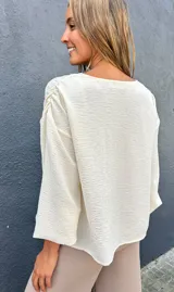 Sobrecamisa de viscosa con detalles de lúrex, color marfil, con escote en V, cierre frontal abotonado y mangas abullonadas.