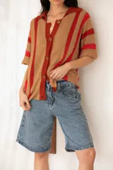 Camisa tejida a rayas horizontales color tostado y rojo, con cuello polo, mangas cortas y botones frontales.