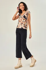 Blusa de poliéster sin mangas, con cuello en V y estampado abstracto multicolor en tonos beige, marrón, negro y naranja.