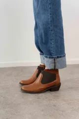 Botín negro de cuero con elásticos laterales, taco bajo y tirador trasero.