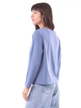 Remera de manga larga color azul, con cuello redondo y un estampado central de flores en tonos pastel sobre un recuadro gris claro.