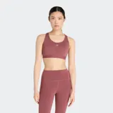 Top deportivo New Balance Essential Run Bra, color rosado oscuro/malva, de soporte completo con escote redondo y espalda deportiva. Presenta un pequeño logo NB reflectante en el frente.