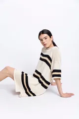 Vestido corto tejido en hilado de algodón con rayas horizontales negras y doradas sobre fondo blanco.