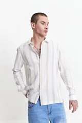 Camisa de manga larga con textura, de corte regular y diseño a rayas verticales en tonos beige y blanco. Presenta cuello clásico y cierre frontal con botones.