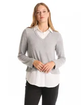 Buzo combinado de hilado fino color gris, con cuello en V y mangas largas. Presenta una pieza inferior y cuello tipo solapa en tela blanca que simula una camisa debajo.