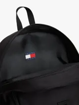 Mochila outdoor Tommy Jeans color negro, con compartimento principal, asa superior, correas ajustables y detalles de malla verde visible en los laterales. Incluye el parche con el logo de la marca bordado en el frente.