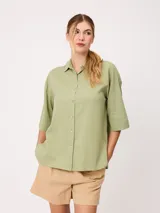 Camisa de manga corta celeste, confeccionada en mezcla de algodón y lino, con cuello camisero y cierre frontal de botones.