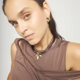 Collar tipo gargantilla con múltiples tiras de hilo de seda o cuero sintético marrón oscuro, unidas por terminales doradas. El dije central es un corazón de metal con acabado dorado martillado y textura irregular.