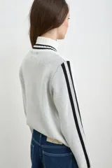 Campera tejida de algodón en color bordó y blanco, con cuello alto, cierre frontal completo y diseño con estampado tipográfico.