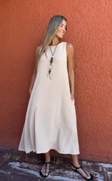 Vestido largo color beige, sin mangas, con cuello redondo y corte en A.