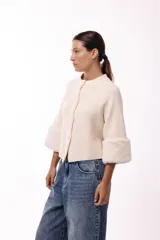 Chaqueta tejida de silueta recta con botones frontales y mangas tres cuartos terminadas en puños de piel sintética suave. Diseño versátil que permite usarla con los botones hacia adelante o hacia atrás.