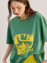 Remera oversize de corte cuadrado, color verde, con cuello redondo y estampa retro centrada en tono amarillo.