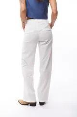 Pantalón blanco de corte recto, con bolsillos laterales y traseros. Se ajusta a la cintura con cinturón de cuero marrón.