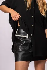 Minifalda negra de cuero con bolsillos frontales y detalles en contraste color hueso.