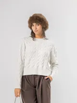 Sweater de punto con diseño de ondas en relieve y tejido con hilo de lurex que aporta un brillo sutil. Presenta cuello redondo, mangas largas y terminaciones en rib acanalado.