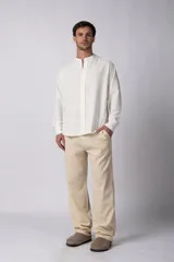 Camisa de manga larga confeccionada en lino, con cuello mao y cierre frontal de botones. Presenta un corte relajado y diseño minimalista.