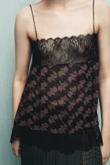 Top estampado con tejido principal de viscosa, escote recto y tirantes finos. Presenta un estampado floral en tonos marrones y negros, con detalles de encaje negro en el escote y el bajo.