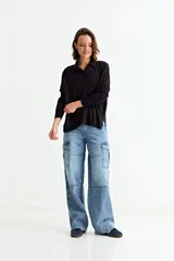 Cardigan de punto negro con cuello camisero, cierre frontal de botones y un bolsillo pequeño en el pecho. Presenta mangas largas y un corte holgado.