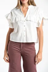 Blusa blanca de algodón con cuello mao, cierre frontal de botones y volados en los hombros con detalle de bordado inglés.