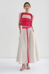 Falda midi color beige, de corte recto y tiro medio, con abertura frontal con botones y bolsillos laterales.