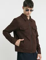 Campera Harrington de gamuza en color marrón, con cierre frontal, cuello clásico y bolsillos laterales con solapa.