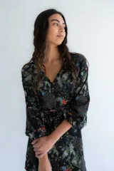 Kimono negro con estampa floral multicolor, escote en V cruzado, mangas largas con elástico en los puños y lazo ancho ajustable en la cintura.