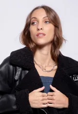 Campera tipo gamulán de símil cuero color marrón oscuro, con interior y solapas de corderito al tono. Presenta cierre frontal cruzado, bolsillos con cierre metálico y hebilla ajustable en el cuello.