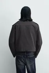 Chaqueta cropped de algodón con cuello mao y manga larga. Presenta un diseño de inspiración militar con alamares decorativos en contraste en el frente, trabillas en los hombros y cierre frontal con ganchos metálicos.